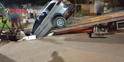 Carro fica preso em bueiro aberto e é removido com ajuda de caminhão guincho, em Pimenta Bueno